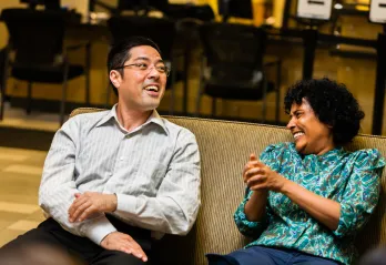 A man and woman sit together, laughing and talking.