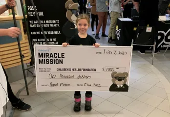 Ella holds a cheque for $1000 dollars she helped raise for the Children's Hospital.