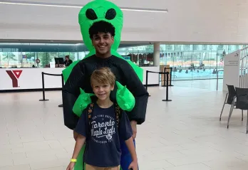 Daniil smiles and poses with a day camp counsellor in costume at the StarTech.com YMCA.
