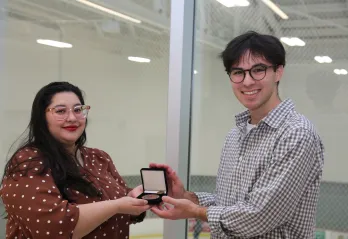 smiling woman with presenting a medal to a taller man 