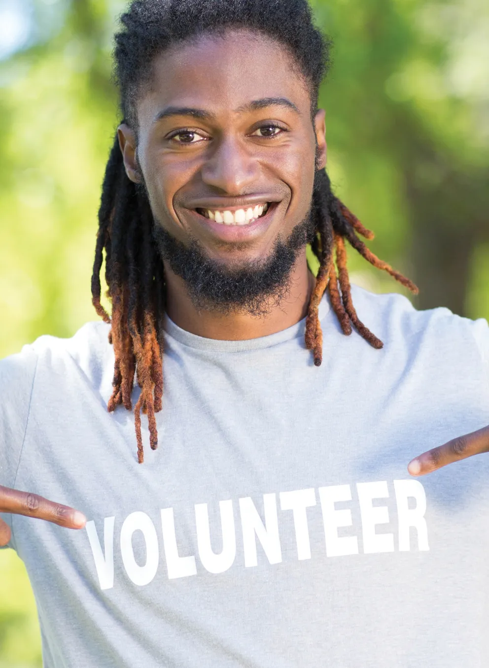 Smiling man pointing to his volunteer t-shirt