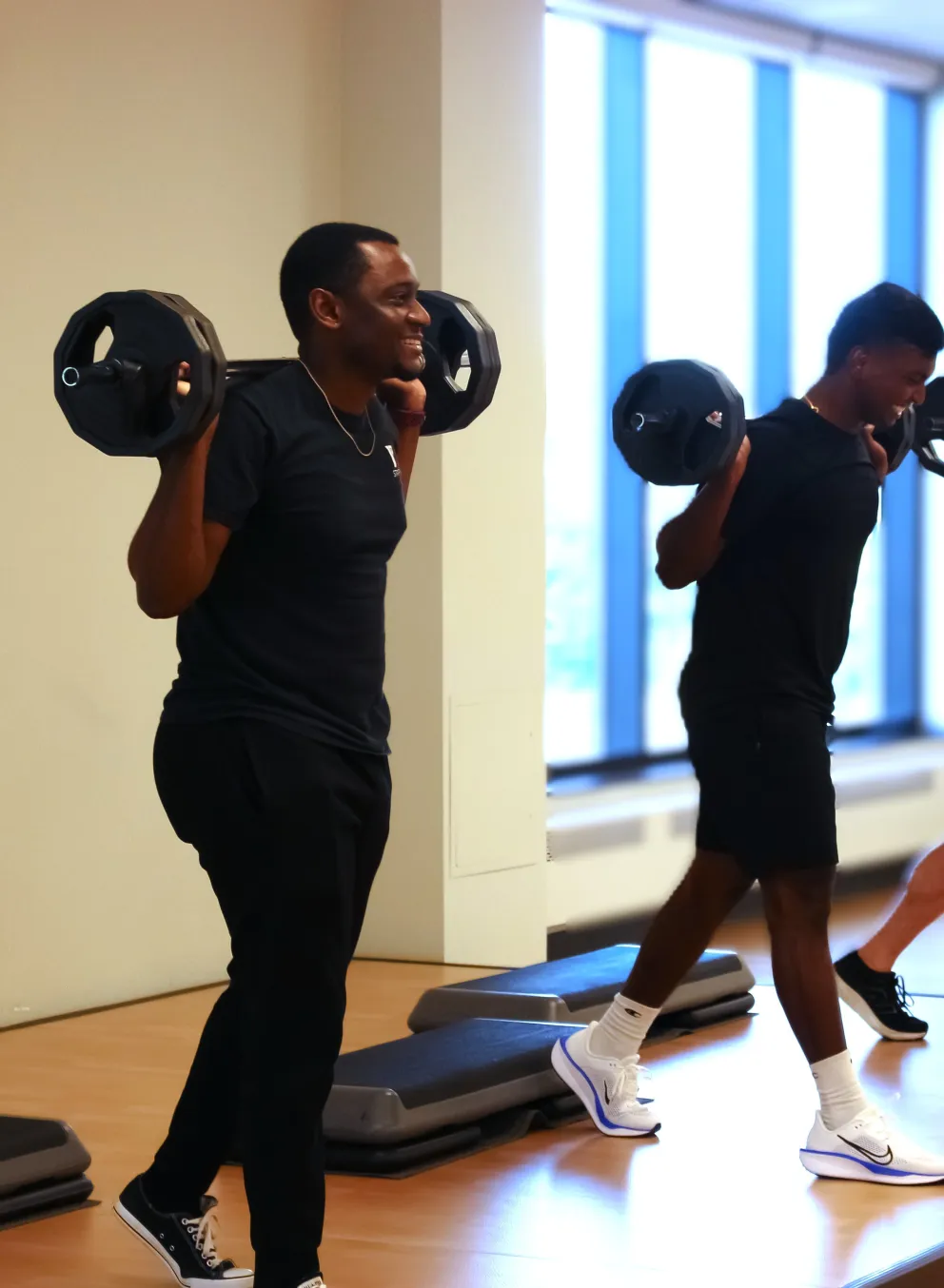 Three men lifting weights in a group fitness class