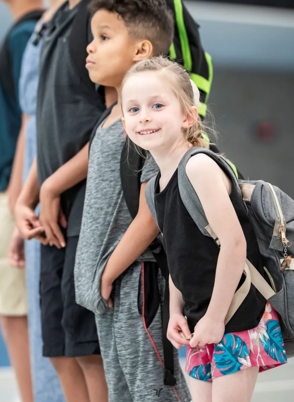Two kids standing with backpacks.