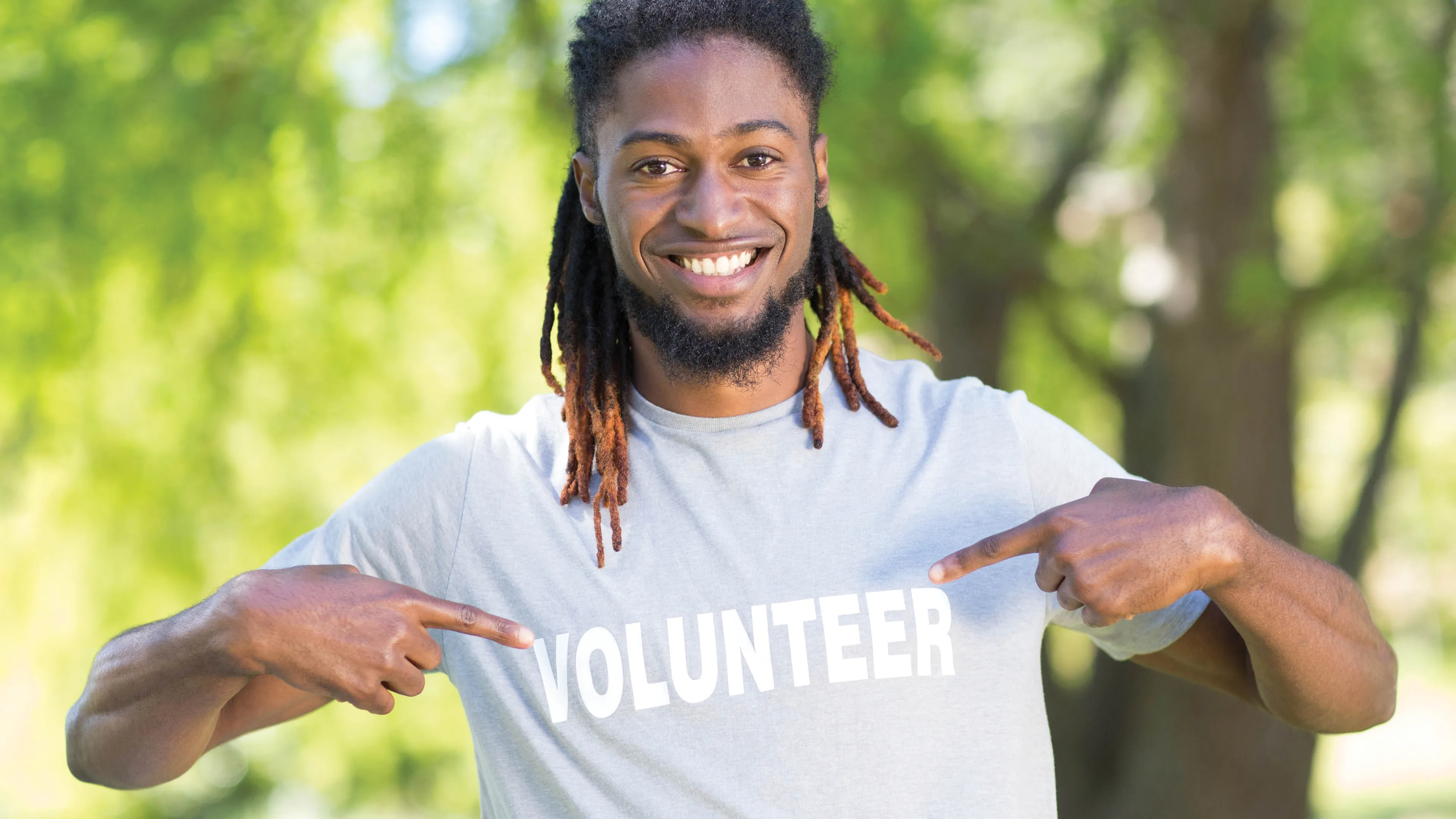 Smiling man pointing to his volunteer t-shirt