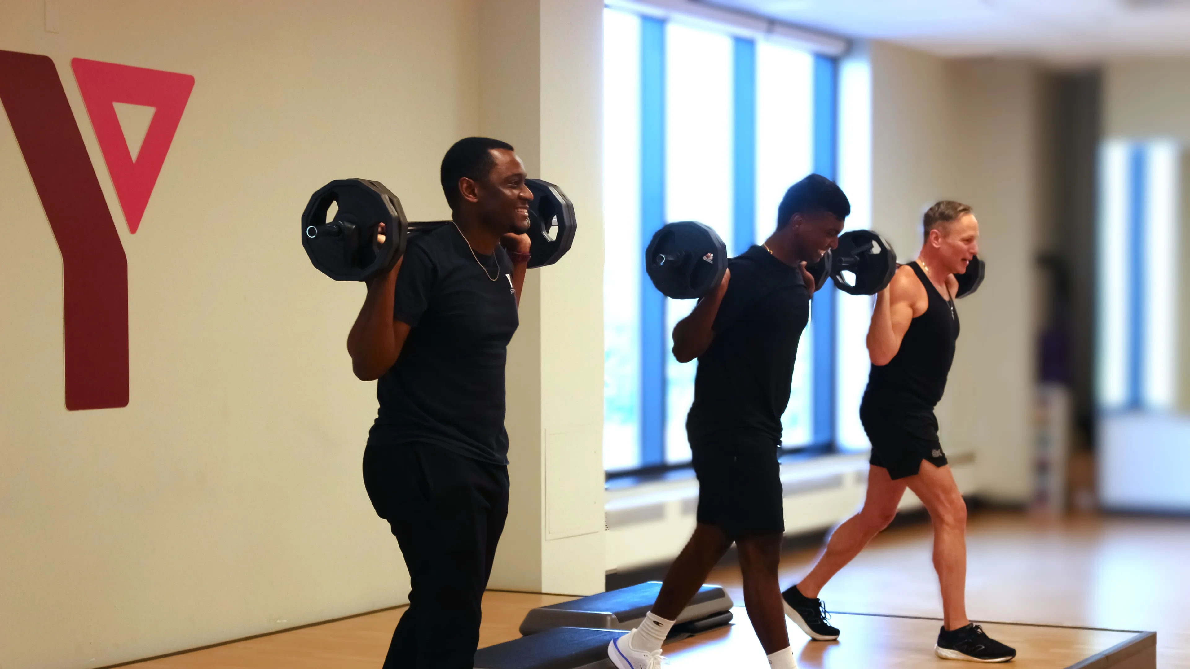 Three men lifting weights in a group fitness class