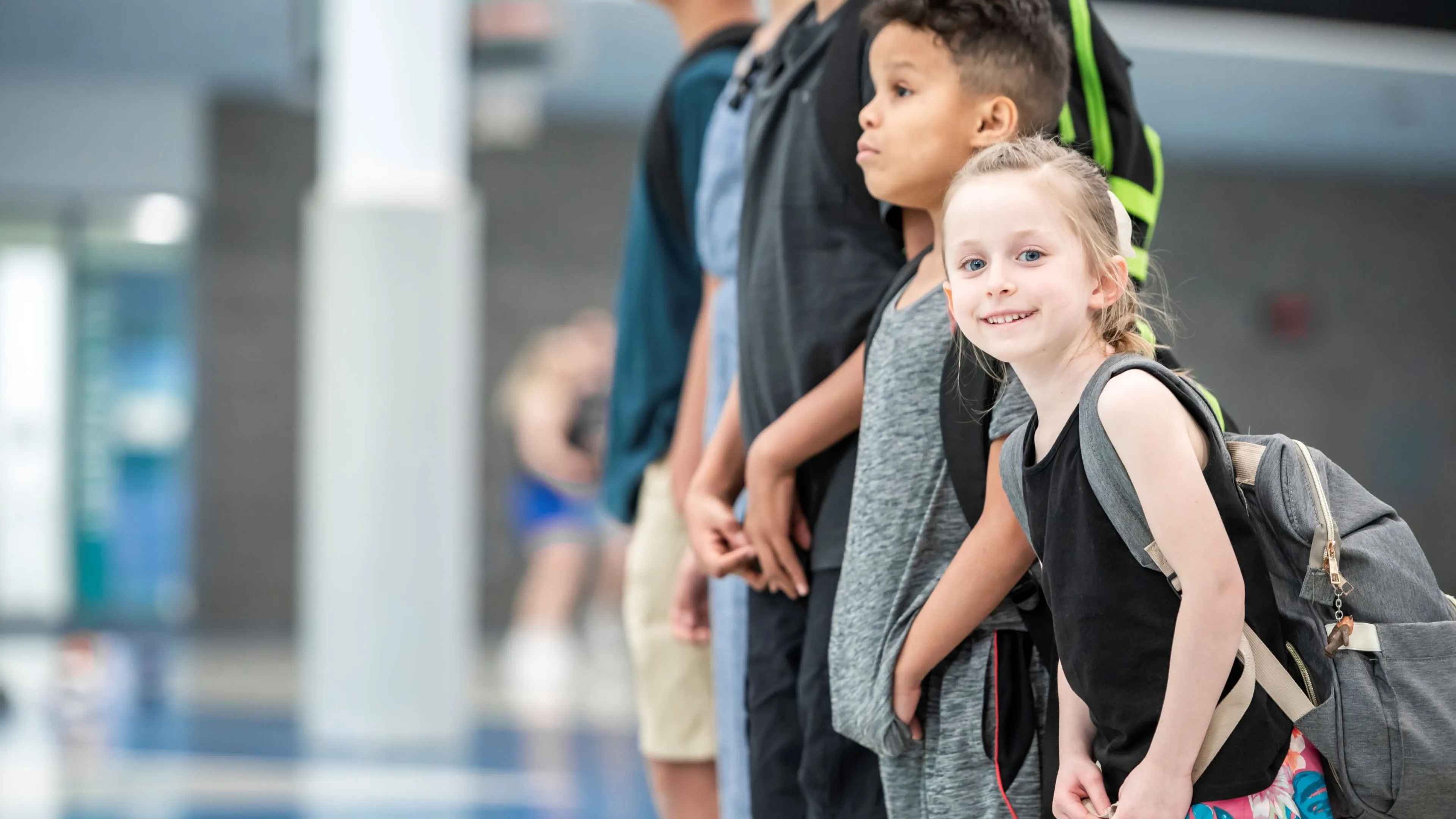 Two kids standing with backpacks.
