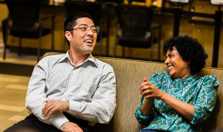 A man and woman sit together, laughing and talking.