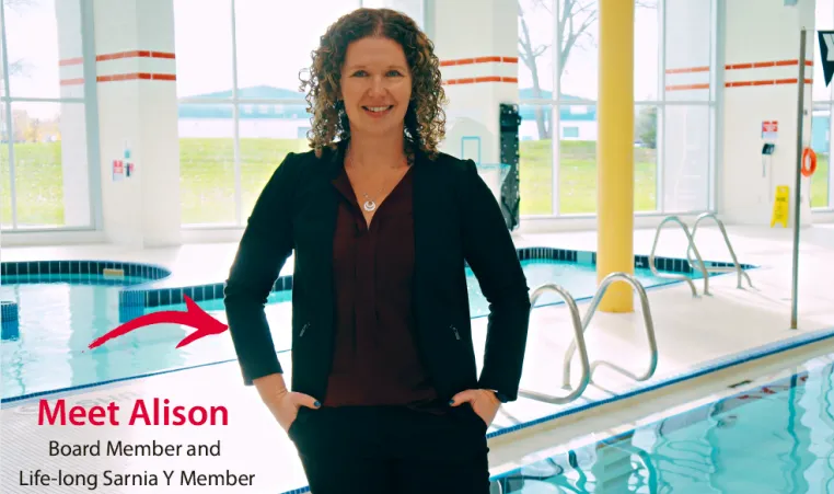 Meet Alison: Board Member and Lifelong Sarnia Y Member. Alison, wearing a black suit and burgundy blouse, stands on the pool deck at the Sarnia YMCA.