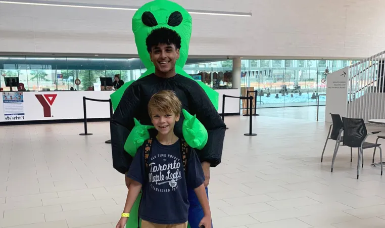 Daniil smiles and poses with a day camp counsellor in costume at the StarTech.com YMCA.