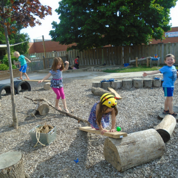 A group of four children explore a YMCA outdoor play space during the summer.