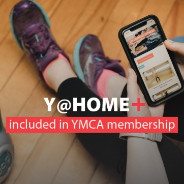 Y@HOME+ included in YMCA membership. Image: a woman in running shoes watches a workout on her mobile device next to a kettlebell.