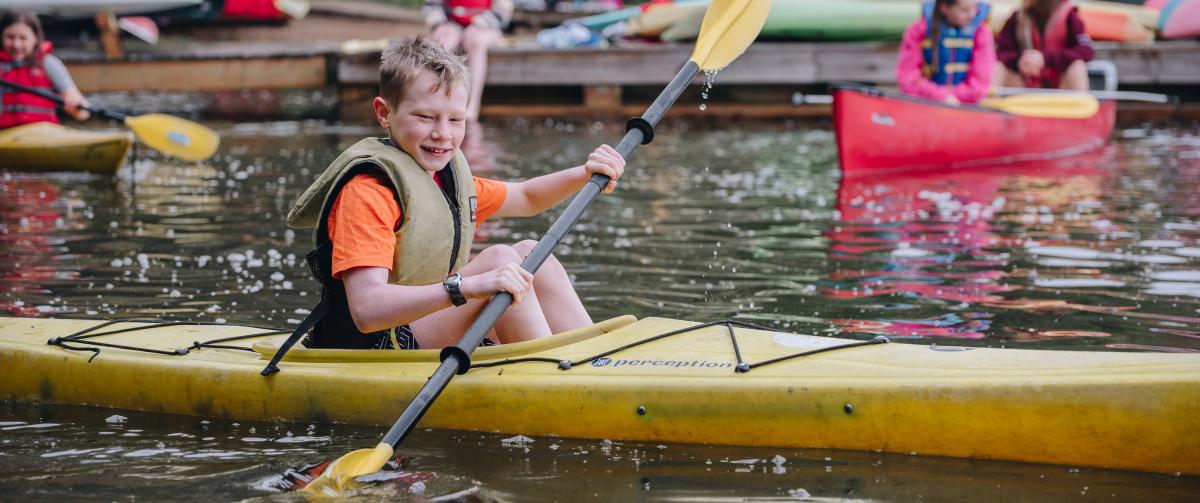 Boy paddling in a yellow kayaking