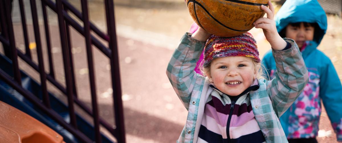 Girl playing outside with a basketball during after care