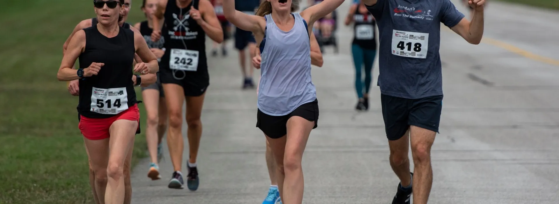 Runners celebrate with hands in the air as they participate in Jordan's Run The Runway.