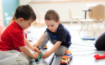 Two young boys play with toy cars at a YMCA Child Care centre.