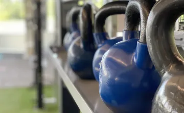 A row of blue and grey kettlebells sits in the turf fitness zone area of a YMCA.