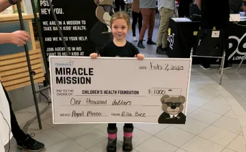 Ella holds a cheque for $1000 dollars she helped raise for the Children's Hospital.