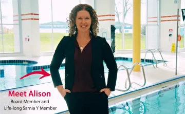 Meet Alison: Board Member and Lifelong Sarnia Y Member. Alison, wearing a black suit and burgundy blouse, stands on the pool deck at the Sarnia YMCA.
