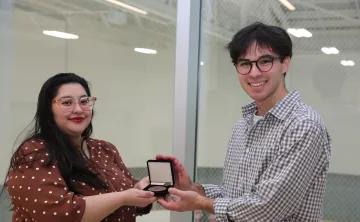 smiling woman with presenting a medal to a taller man 